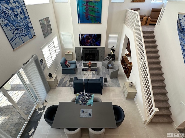 living room with light tile patterned flooring, a fireplace, and a high ceiling