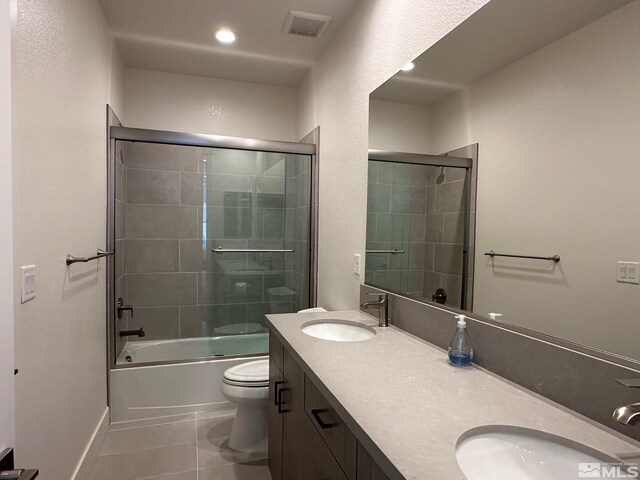 full bathroom featuring tile patterned floors, shower / bath combination with glass door, vanity, and toilet