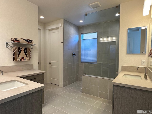 bathroom featuring tile patterned floors, vanity, and a tile shower