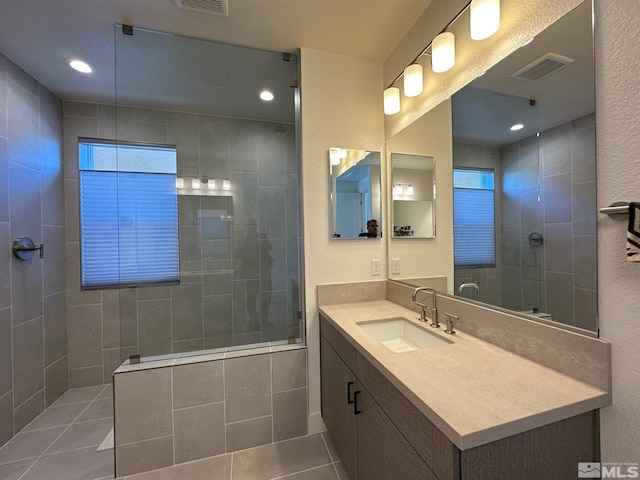 bathroom with tile patterned floors, vanity, and a tile shower