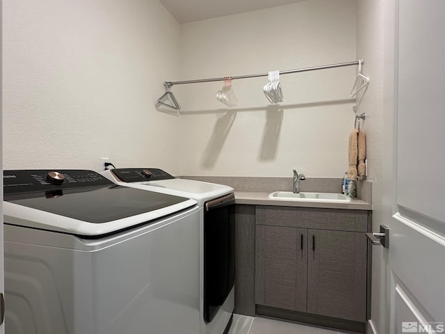 clothes washing area with cabinets, washer and clothes dryer, and sink