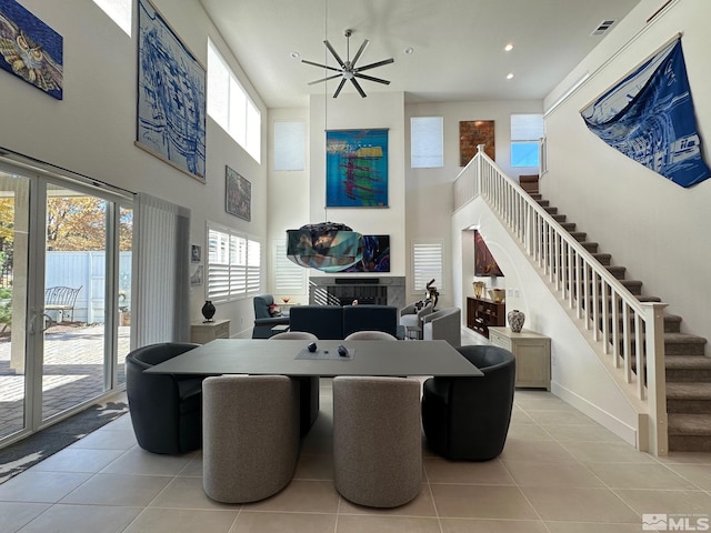 tiled dining area featuring a high ceiling, ceiling fan, and a tiled fireplace