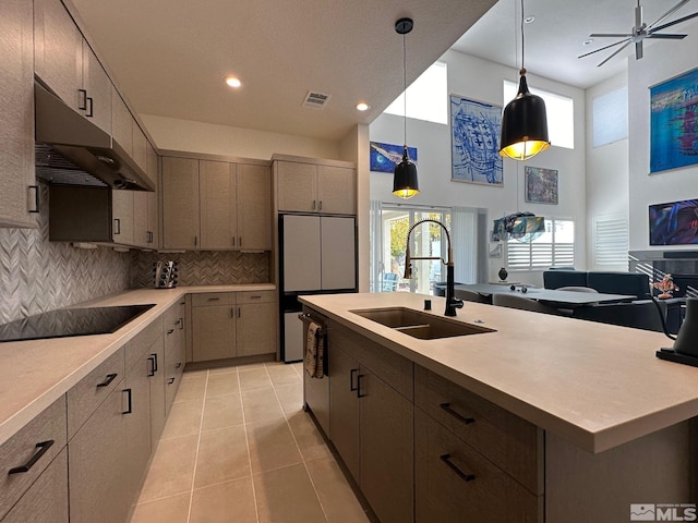 kitchen with black electric stovetop, sink, decorative backsplash, light tile patterned floors, and decorative light fixtures