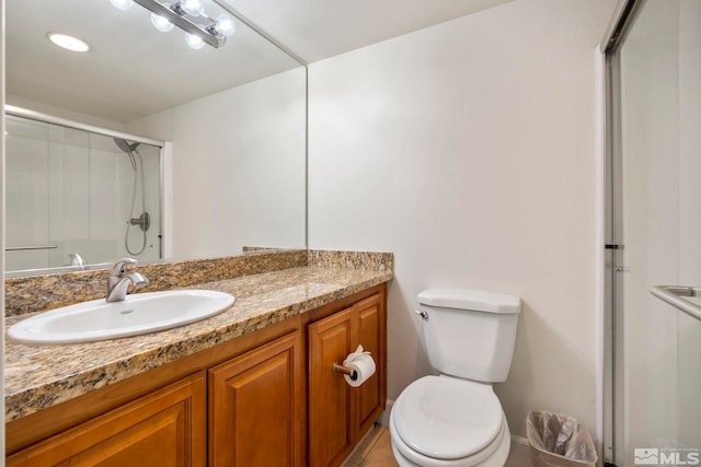 bathroom featuring tile patterned flooring, vanity, toilet, and walk in shower