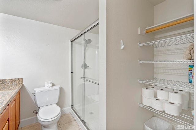 bathroom featuring tile patterned floors, vanity, a shower with shower door, and toilet