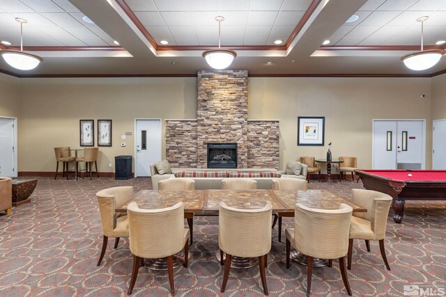 interior space with a high ceiling, a raised ceiling, crown molding, a fireplace, and pool table