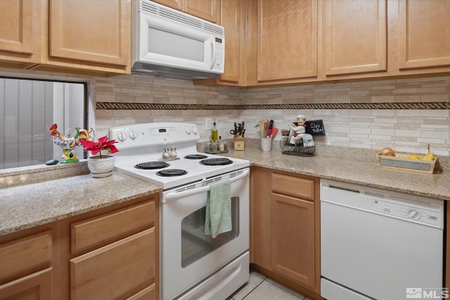 kitchen with decorative backsplash, light stone countertops, white appliances, and light tile patterned floors