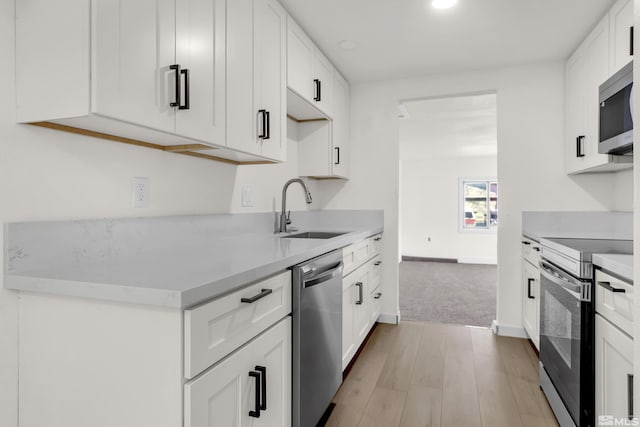 kitchen featuring appliances with stainless steel finishes, light hardwood / wood-style flooring, white cabinetry, and sink