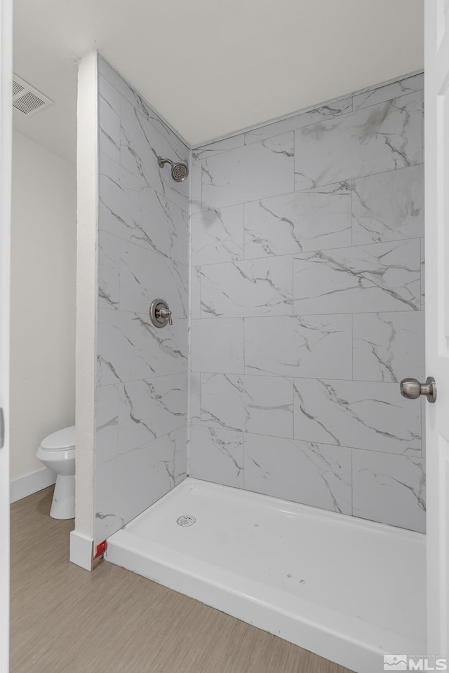 bathroom featuring toilet and a tile shower