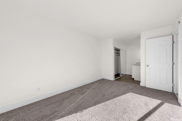 unfurnished bedroom featuring a closet and dark carpet