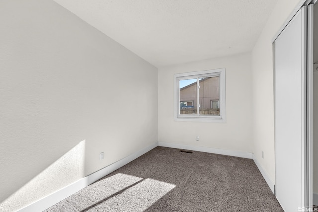 unfurnished room featuring dark colored carpet