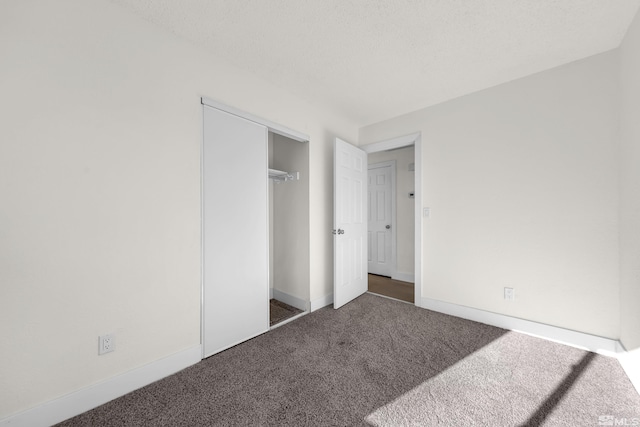 unfurnished bedroom with dark carpet, a textured ceiling, and a closet