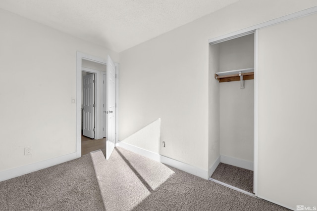 unfurnished bedroom featuring a closet, a textured ceiling, and dark colored carpet