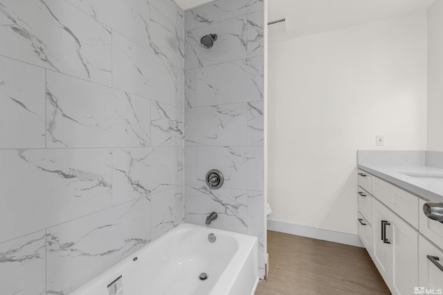 bathroom with wood-type flooring, vanity, and tiled shower / bath