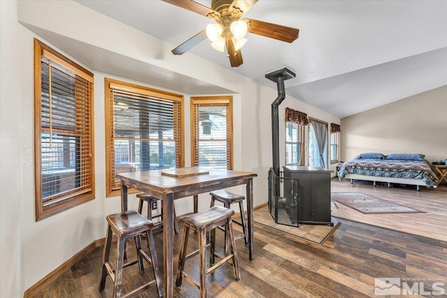 dining area featuring a wood stove, ceiling fan, lofted ceiling, and hardwood / wood-style flooring