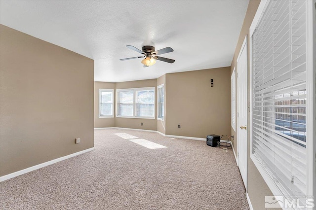 carpeted empty room with ceiling fan and a textured ceiling