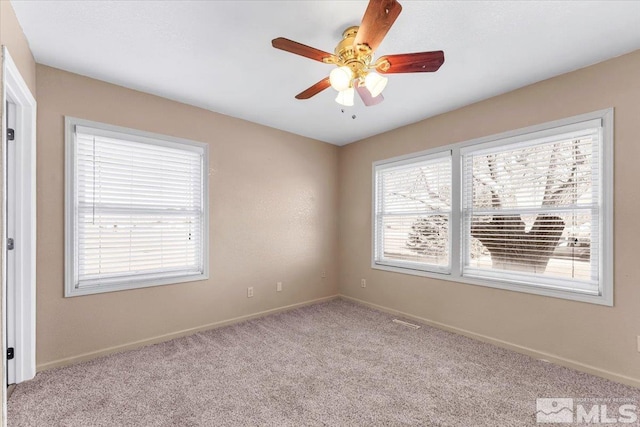 empty room featuring plenty of natural light, ceiling fan, and light carpet