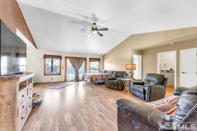 living room with a textured ceiling, ceiling fan, light hardwood / wood-style flooring, and vaulted ceiling