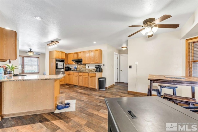 kitchen with light stone countertops, a textured ceiling, extractor fan, dark wood-type flooring, and light brown cabinets