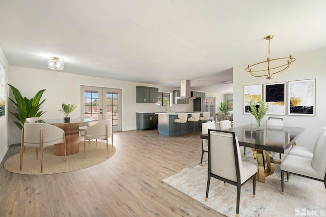 dining room featuring french doors, light wood-type flooring, and a notable chandelier