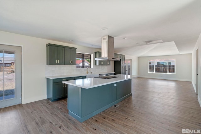 kitchen featuring a wealth of natural light, island range hood, tasteful backsplash, and light hardwood / wood-style floors