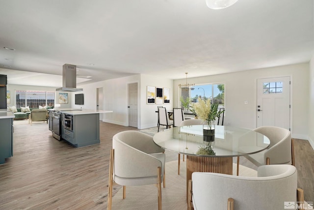 dining area with plenty of natural light, light hardwood / wood-style floors, and an inviting chandelier