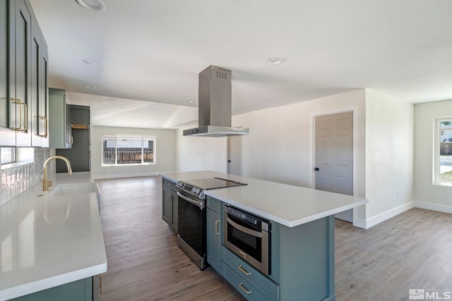 kitchen with electric range, a center island, sink, light hardwood / wood-style floors, and island range hood