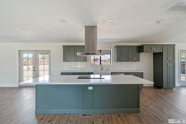 kitchen with french doors, tasteful backsplash, island range hood, black electric cooktop, and a kitchen island