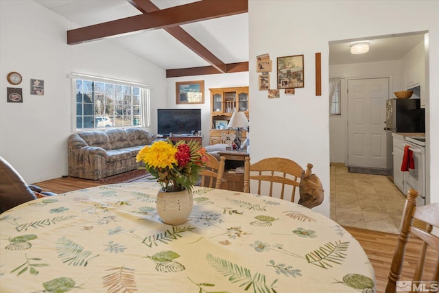 dining room featuring vaulted ceiling with beams and light wood-type flooring