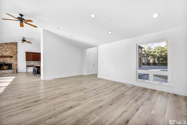 unfurnished living room featuring ceiling fan, a fireplace, light hardwood / wood-style floors, and vaulted ceiling