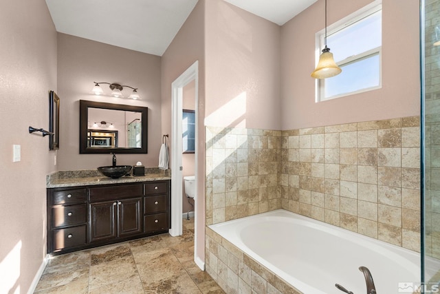 bathroom featuring vanity, toilet, and tiled bath