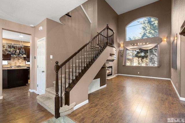 stairs with wood-type flooring and a high ceiling