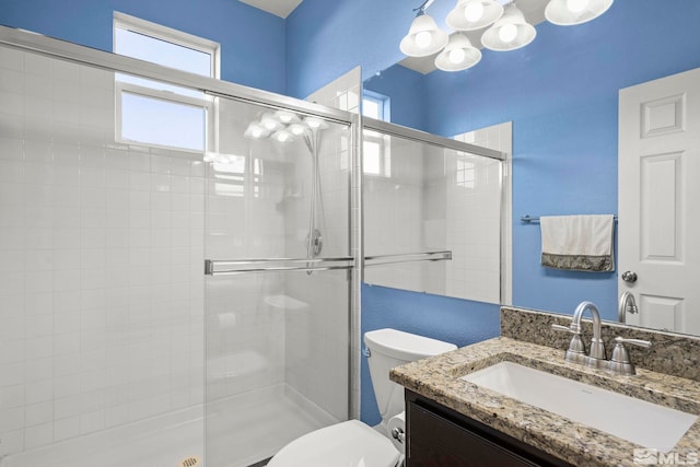 bathroom with a shower with door, vanity, a healthy amount of sunlight, and toilet