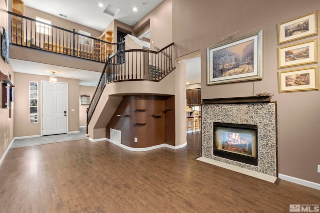 interior space with a healthy amount of sunlight, a multi sided fireplace, wood-type flooring, and a high ceiling