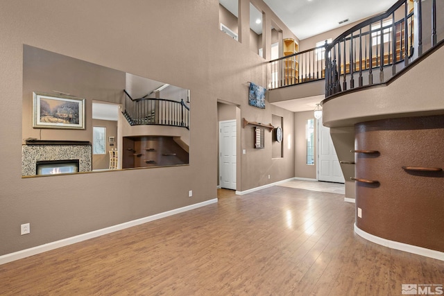 unfurnished living room with hardwood / wood-style flooring, a towering ceiling, and a fireplace