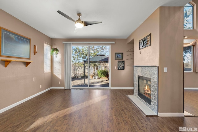 unfurnished living room featuring dark hardwood / wood-style flooring, ceiling fan, and a fireplace