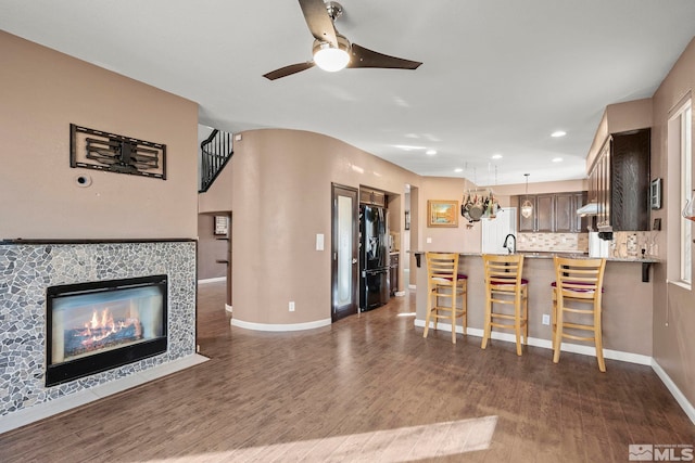 interior space featuring a tiled fireplace, ceiling fan, and dark wood-type flooring