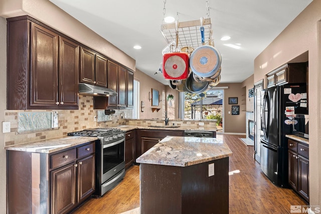 kitchen with black fridge, sink, stainless steel gas range, decorative backsplash, and a kitchen island