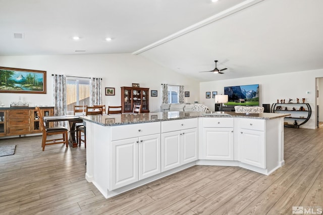 kitchen featuring light wood-type flooring, white cabinetry, ceiling fan, and dark stone counters