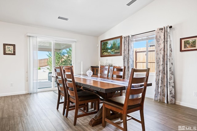 dining area with hardwood / wood-style flooring, vaulted ceiling, and a healthy amount of sunlight