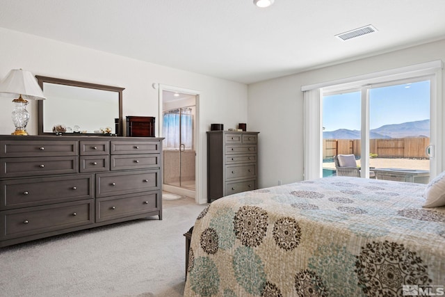 bedroom with a mountain view, ensuite bathroom, and light colored carpet