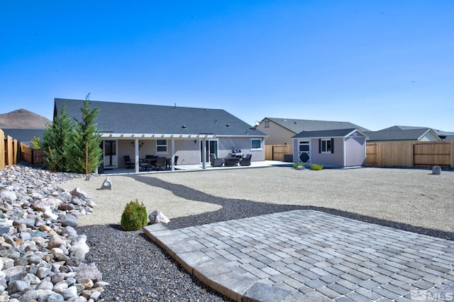 rear view of house with a storage unit and a patio area