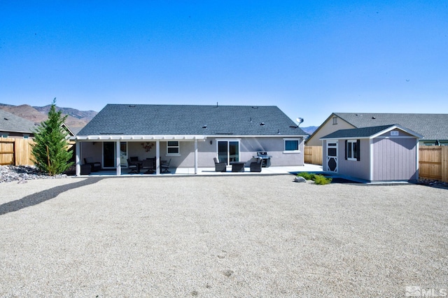 back of house with a mountain view, a patio, and a storage unit