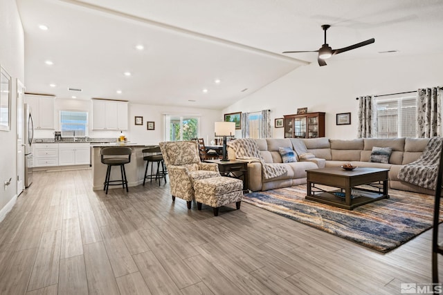 living room with lofted ceiling with beams, ceiling fan, and light hardwood / wood-style floors