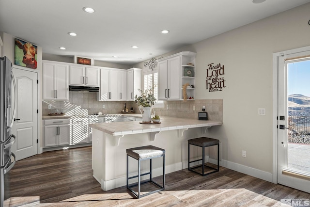 kitchen featuring kitchen peninsula, dark hardwood / wood-style flooring, tile countertops, and white cabinetry