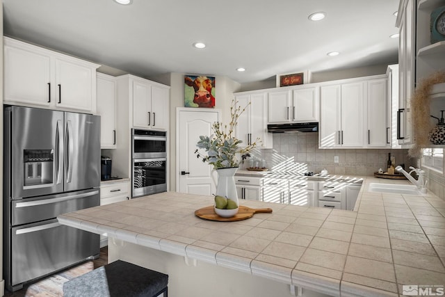 kitchen with tile counters, white cabinetry, sink, and appliances with stainless steel finishes