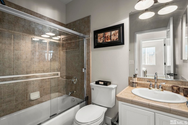 full bathroom with combined bath / shower with glass door, vanity, and toilet