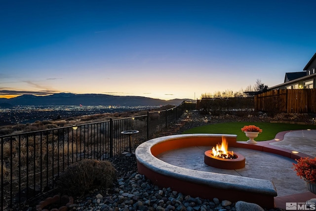 patio terrace at dusk featuring a mountain view and an outdoor fire pit