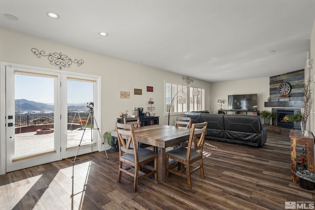 dining room with a mountain view, a large fireplace, and dark hardwood / wood-style flooring