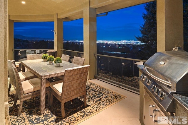 patio terrace at dusk with a balcony and area for grilling